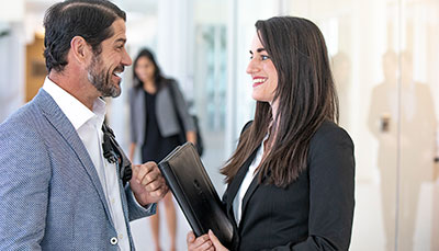 Two business professionals talking in a hallway.